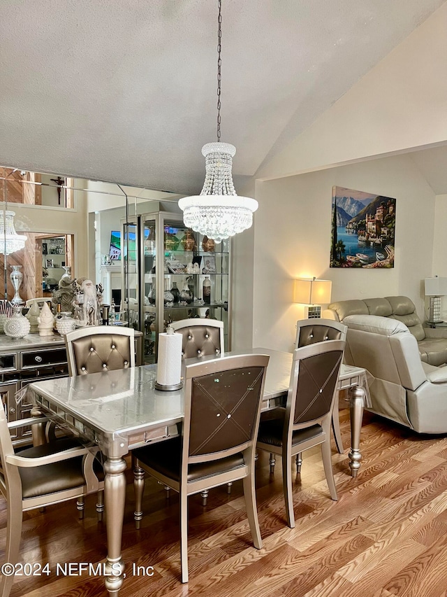 dining area featuring vaulted ceiling, an inviting chandelier, light hardwood / wood-style floors, and a textured ceiling