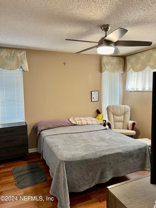 bedroom with ceiling fan, a textured ceiling, and wood-type flooring