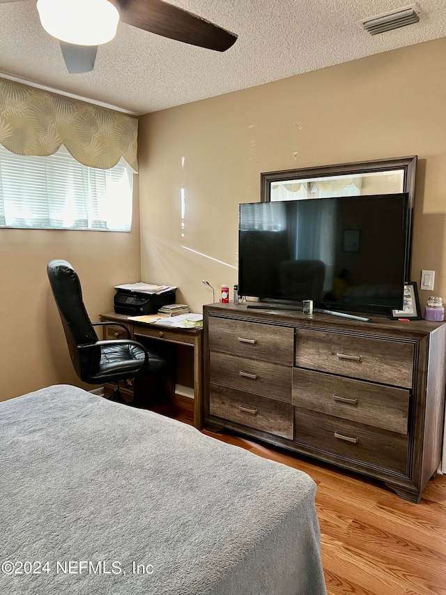 bedroom with light hardwood / wood-style flooring, ceiling fan, and a textured ceiling