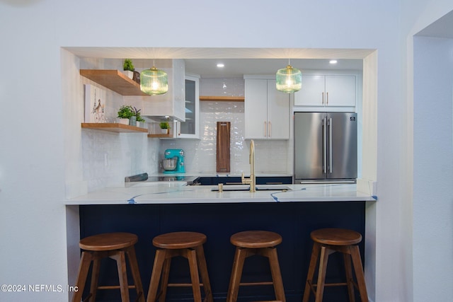 kitchen with white cabinetry, high end fridge, tasteful backsplash, and a breakfast bar