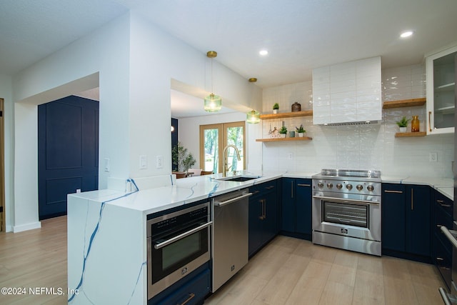 kitchen with stainless steel appliances, kitchen peninsula, sink, pendant lighting, and light wood-type flooring