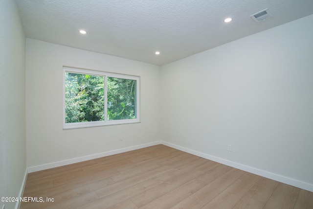 unfurnished room featuring a textured ceiling and light hardwood / wood-style floors