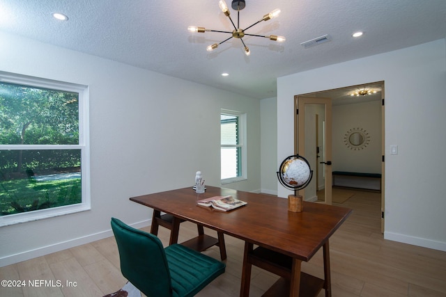 dining area featuring a wealth of natural light, a textured ceiling, a chandelier, and light hardwood / wood-style flooring