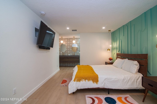 bedroom with a textured ceiling and light hardwood / wood-style floors