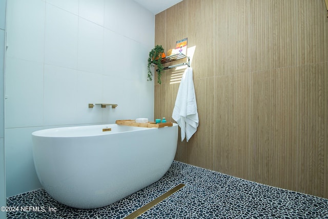 bathroom with a tub, tile patterned flooring, and tile walls