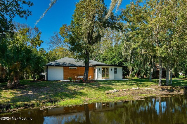 back of property with a yard and a water view