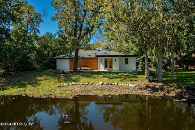 back of property featuring a yard, french doors, and a water view