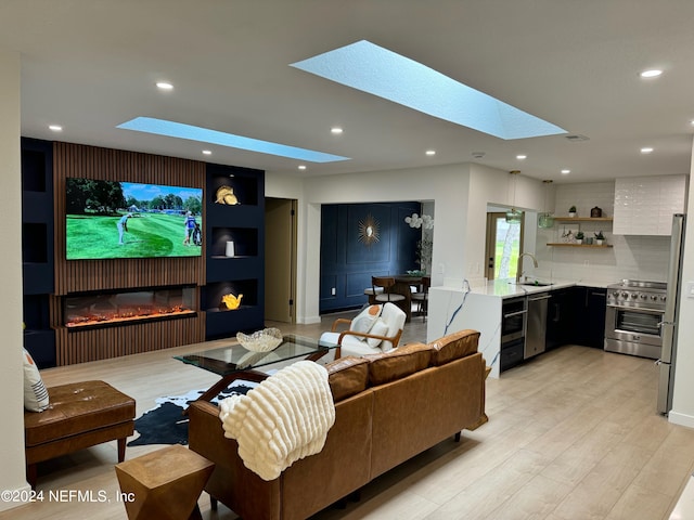 home theater room featuring sink, light hardwood / wood-style flooring, and a skylight