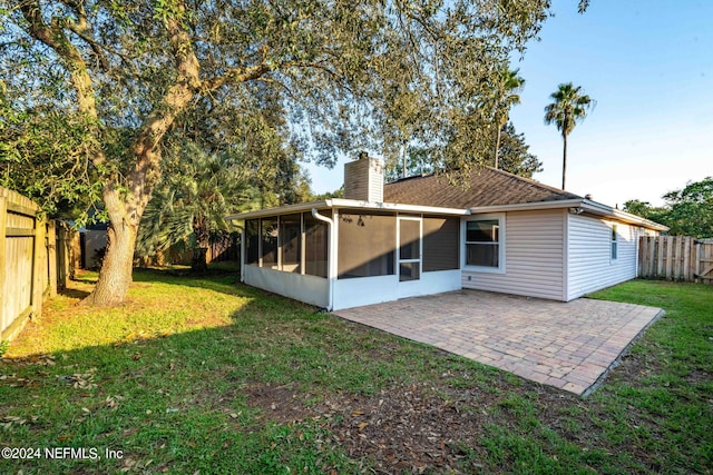 back of property with a yard, a sunroom, and a patio