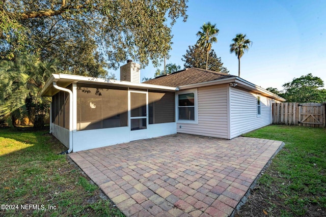 rear view of property with a yard, a sunroom, and a patio area