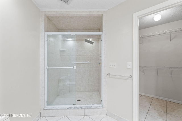 bathroom featuring a shower with door, tile patterned floors, and a textured ceiling