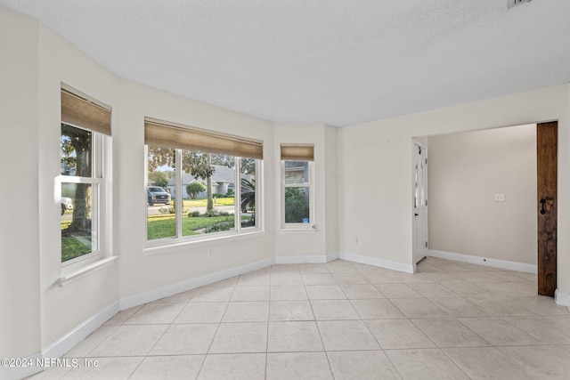 tiled empty room with a textured ceiling