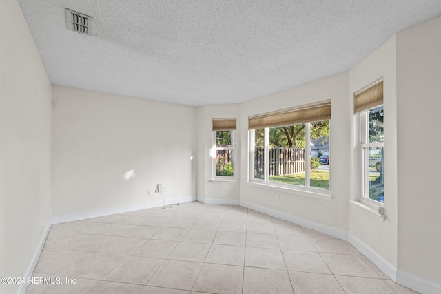 empty room featuring a textured ceiling and light tile patterned flooring