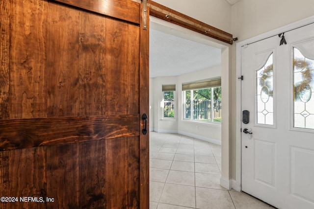 entryway featuring light tile patterned floors, a textured ceiling, a wealth of natural light, and a barn door