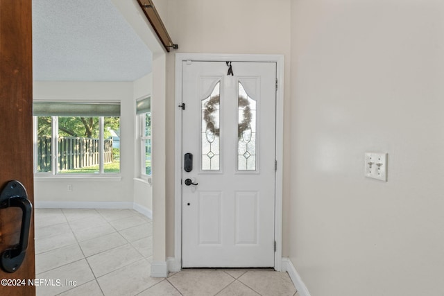 foyer with a textured ceiling and light tile patterned floors