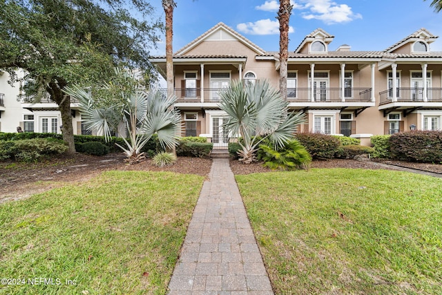 view of front of house featuring a balcony and a front lawn