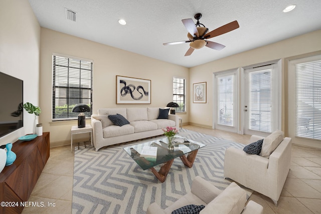 living room with light tile patterned floors, a textured ceiling, and a healthy amount of sunlight