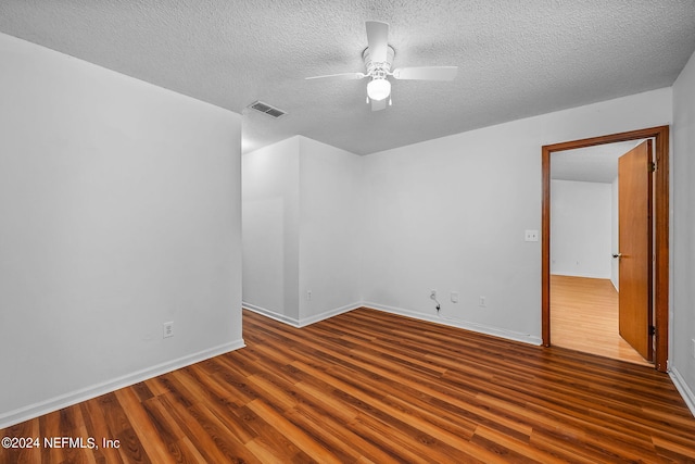 spare room with ceiling fan, visible vents, baseboards, a textured ceiling, and wood finished floors