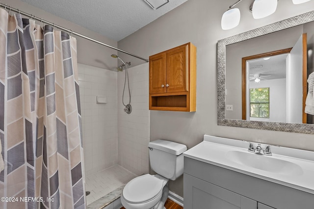 bathroom with a textured ceiling, a shower with curtain, ceiling fan, vanity, and toilet