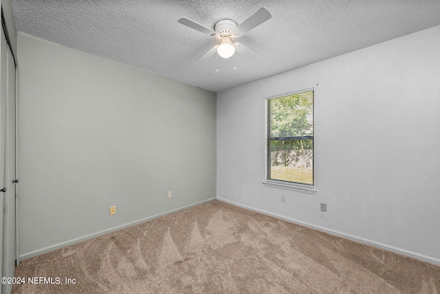 carpeted spare room featuring a textured ceiling, a ceiling fan, and baseboards