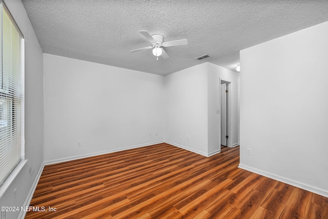 spare room featuring visible vents, wood finished floors, a ceiling fan, and a textured ceiling