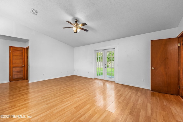 unfurnished room featuring ceiling fan, lofted ceiling, french doors, a textured ceiling, and light hardwood / wood-style flooring