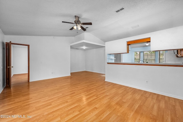 unfurnished living room featuring ceiling fan, a textured ceiling, light wood-type flooring, and vaulted ceiling