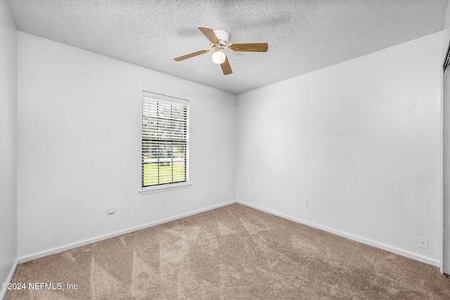 carpeted spare room with a textured ceiling, ceiling fan, and baseboards