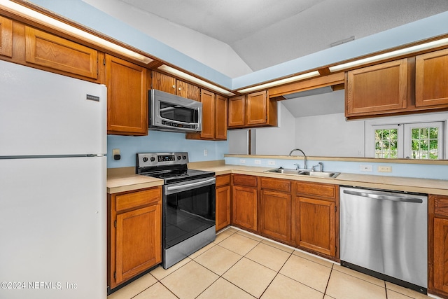 kitchen with appliances with stainless steel finishes, lofted ceiling, sink, and light tile patterned floors