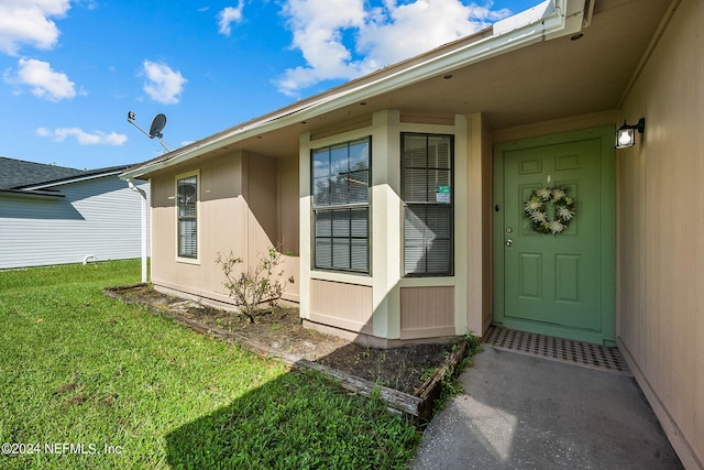 view of exterior entry with a yard