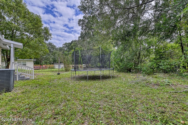 view of yard with central AC unit and a trampoline