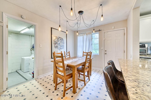 dining space featuring washing machine and dryer, wooden walls, and a notable chandelier