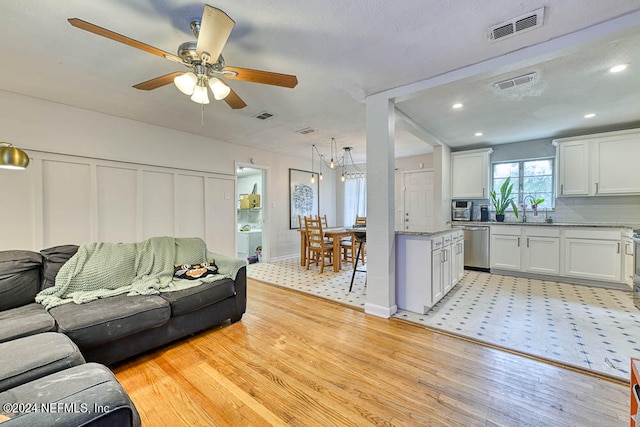 living room featuring ceiling fan, a textured ceiling, light hardwood / wood-style flooring, and sink