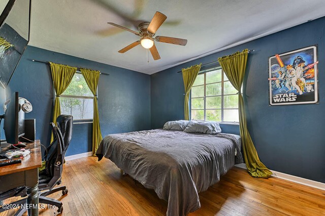 bedroom with ceiling fan, hardwood / wood-style flooring, and multiple windows