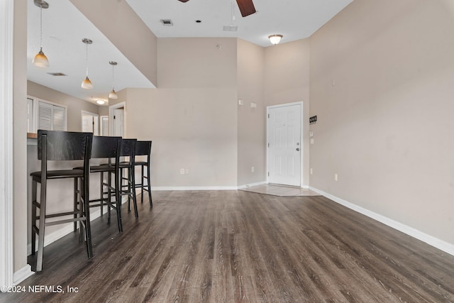 living room featuring ceiling fan, dark hardwood / wood-style flooring, and a high ceiling