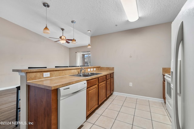 kitchen with pendant lighting, sink, kitchen peninsula, a kitchen bar, and white appliances