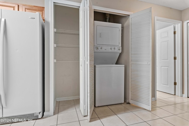 washroom featuring stacked washing maching and dryer and light tile patterned floors