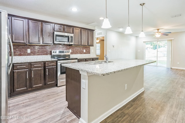 kitchen with light wood-type flooring, ceiling fan, pendant lighting, sink, and appliances with stainless steel finishes