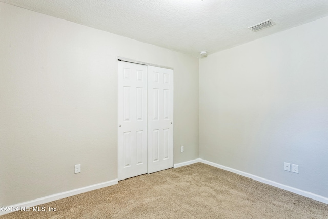 unfurnished bedroom featuring carpet floors, a closet, and a textured ceiling