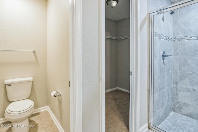 bathroom featuring tile patterned flooring, toilet, and a shower with door