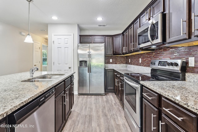 kitchen featuring light hardwood / wood-style floors, dark brown cabinetry, decorative light fixtures, sink, and appliances with stainless steel finishes