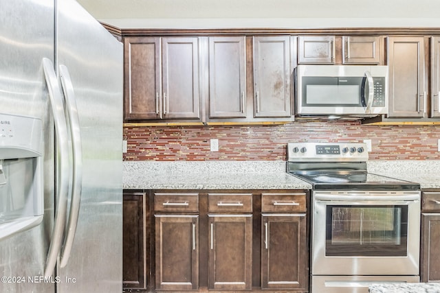 kitchen featuring tasteful backsplash, light stone countertops, appliances with stainless steel finishes, and dark brown cabinetry