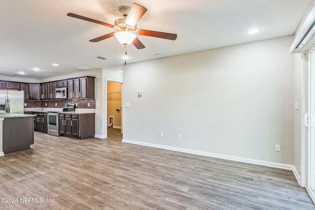 kitchen featuring dark brown cabinetry, ceiling fan, backsplash, appliances with stainless steel finishes, and hardwood / wood-style floors