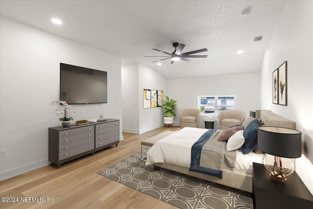 bedroom featuring a textured ceiling, vaulted ceiling, ceiling fan, and light hardwood / wood-style flooring