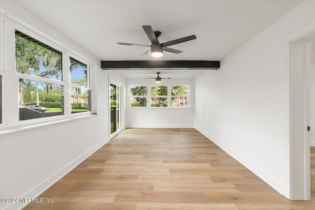 interior space with light wood-type flooring, a healthy amount of sunlight, a textured ceiling, and beamed ceiling