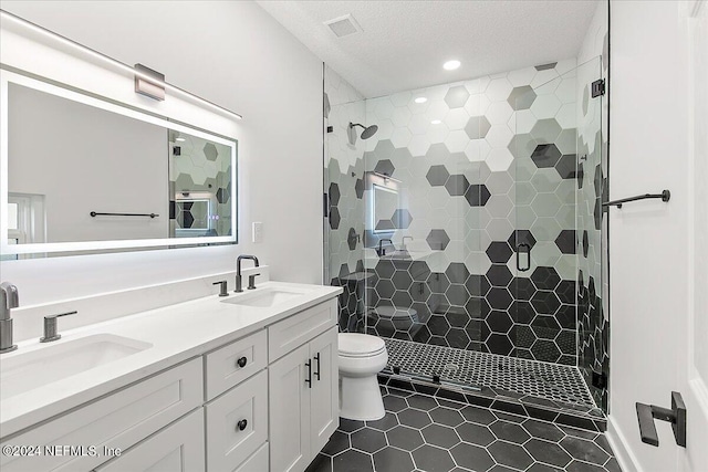 bathroom with vanity, toilet, a textured ceiling, tile patterned flooring, and a shower with door