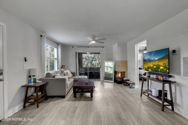 living room featuring light hardwood / wood-style flooring, ceiling fan, and a fireplace