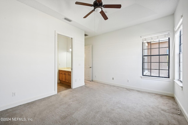 unfurnished bedroom featuring light carpet, ensuite bathroom, and ceiling fan