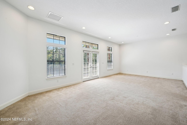 carpeted spare room featuring french doors