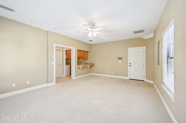 unfurnished living room featuring light colored carpet, sink, and ceiling fan